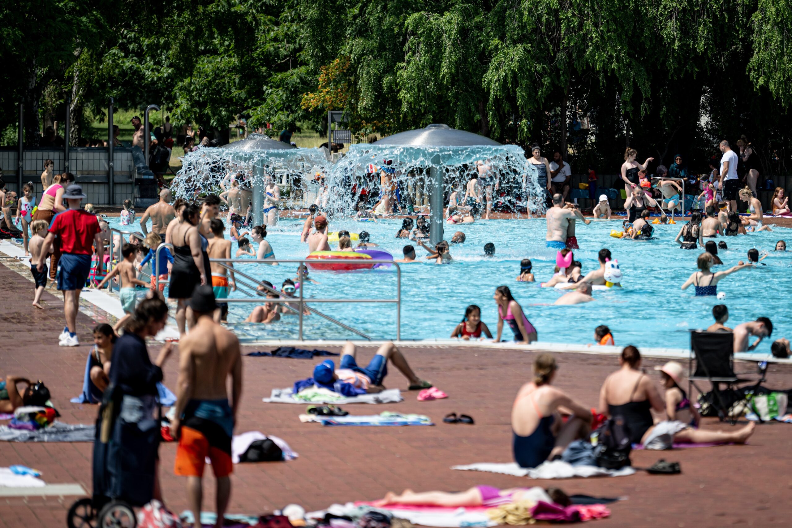 Menschen vor einem Freibadschwimmbecken liegend