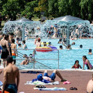 Menschen vor einem Freibadschwimmbecken liegend