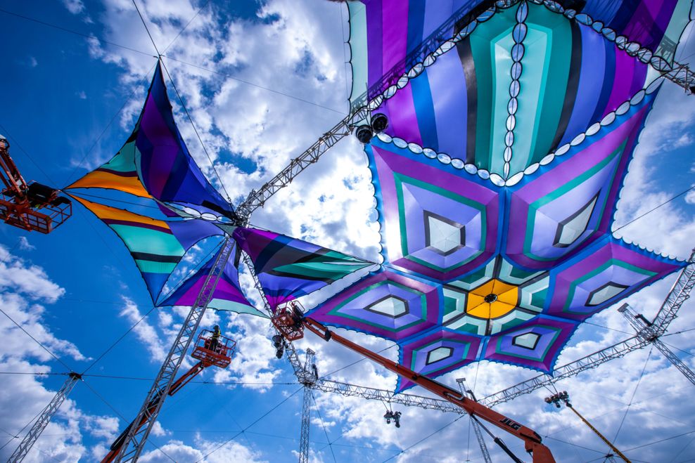 Techniker spannen farbige Planen über eine der Bühnen für das Musikfestival Airbeat One auf dem Flugplatz.