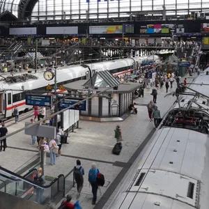 Gleise des Hamburger Hauptbahnhofs mit Zügen und dem großen Glasfenster im Hintergrund
