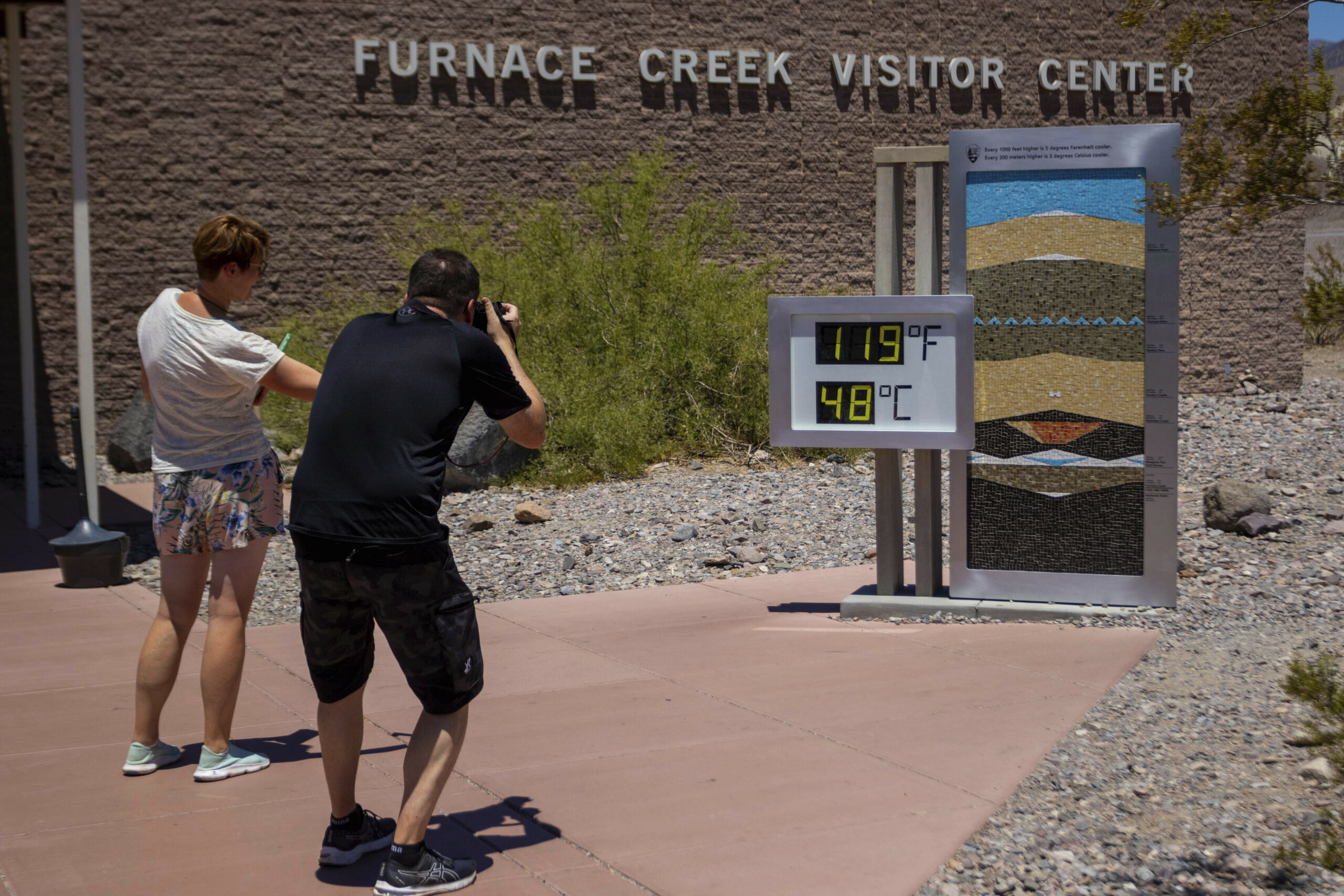 Menschen bleiben stehen, um Fotos von einem Thermostat zu machen, der 119° Fahrenheit (48° Celsius) im Furnace Creek Besucherzentrumim Death Valley National Park, Kalifornien, anzeigt.