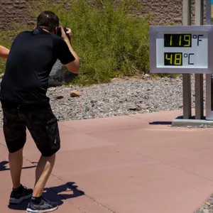 Menschen bleiben stehen, um Fotos von einem Thermostat zu machen, der 119° Fahrenheit (48° Celsius) im Furnace Creek Besucherzentrumim Death Valley National Park, Kalifornien, anzeigt.