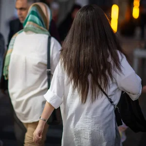 Eine Frau läuft in Teheran mit offenen Haaren am Abend eine Straße entlang.