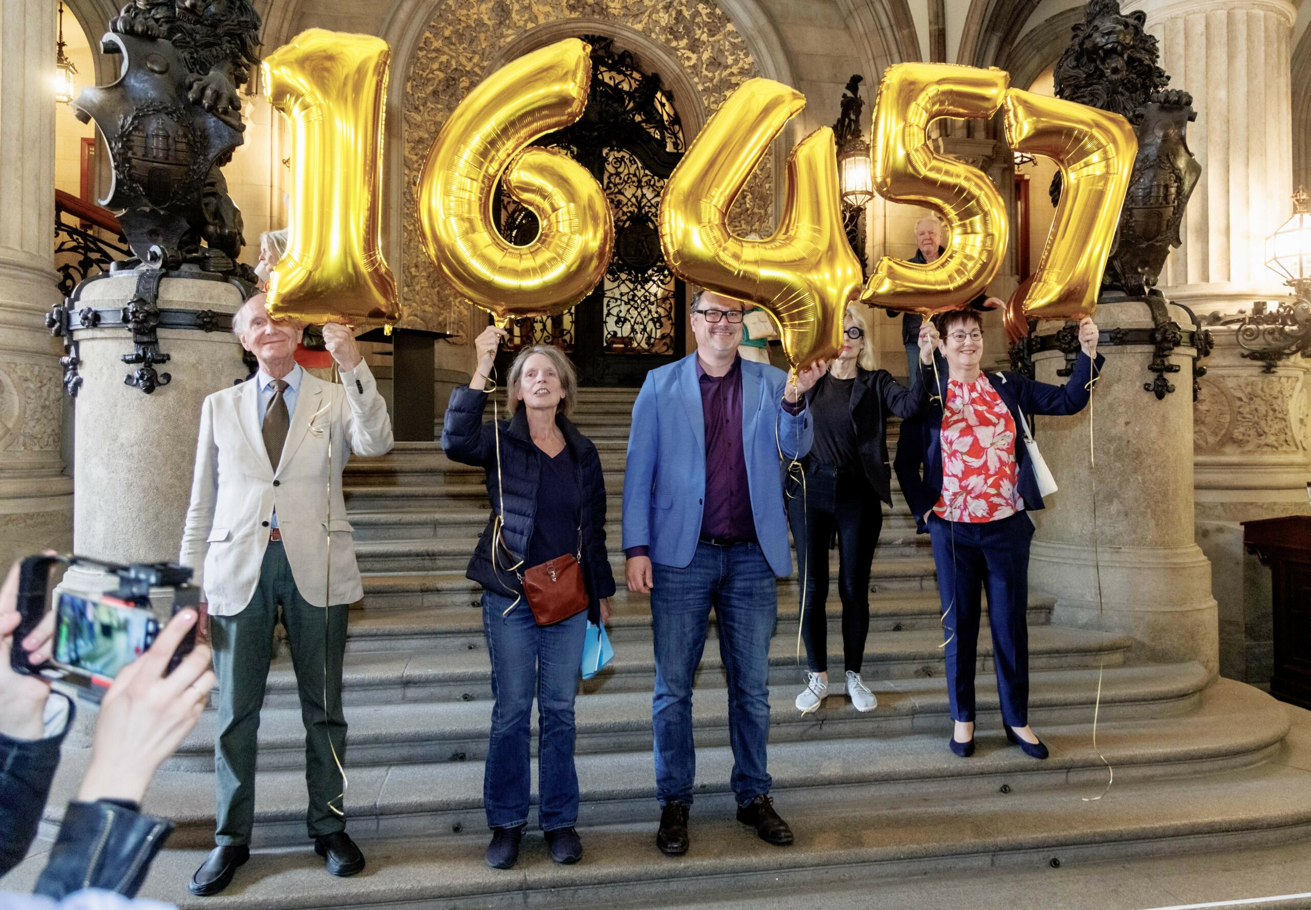 Mitglieder der Volksinitiative «Schluss mit Gendersprache in Verwaltung und Bildung» halten im Rathaus Ballons mit der Zahl 16457 in die Höhe. So viele Unterschriften hat die Volksinitiative kurz zuvor an den Hamburger Senat übergeben.