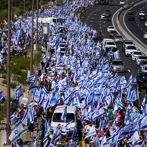 Israel-Fahnen werden von Demonstrierenden über die Autobahn getragen.