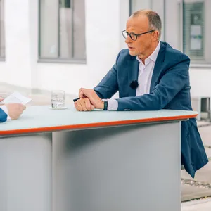 CDU-Parteichef Friedrich Merz (r.) sitzt im ZDF-Sommerinterview gegenüber von Moderator Theo Koll an einem Tisch.