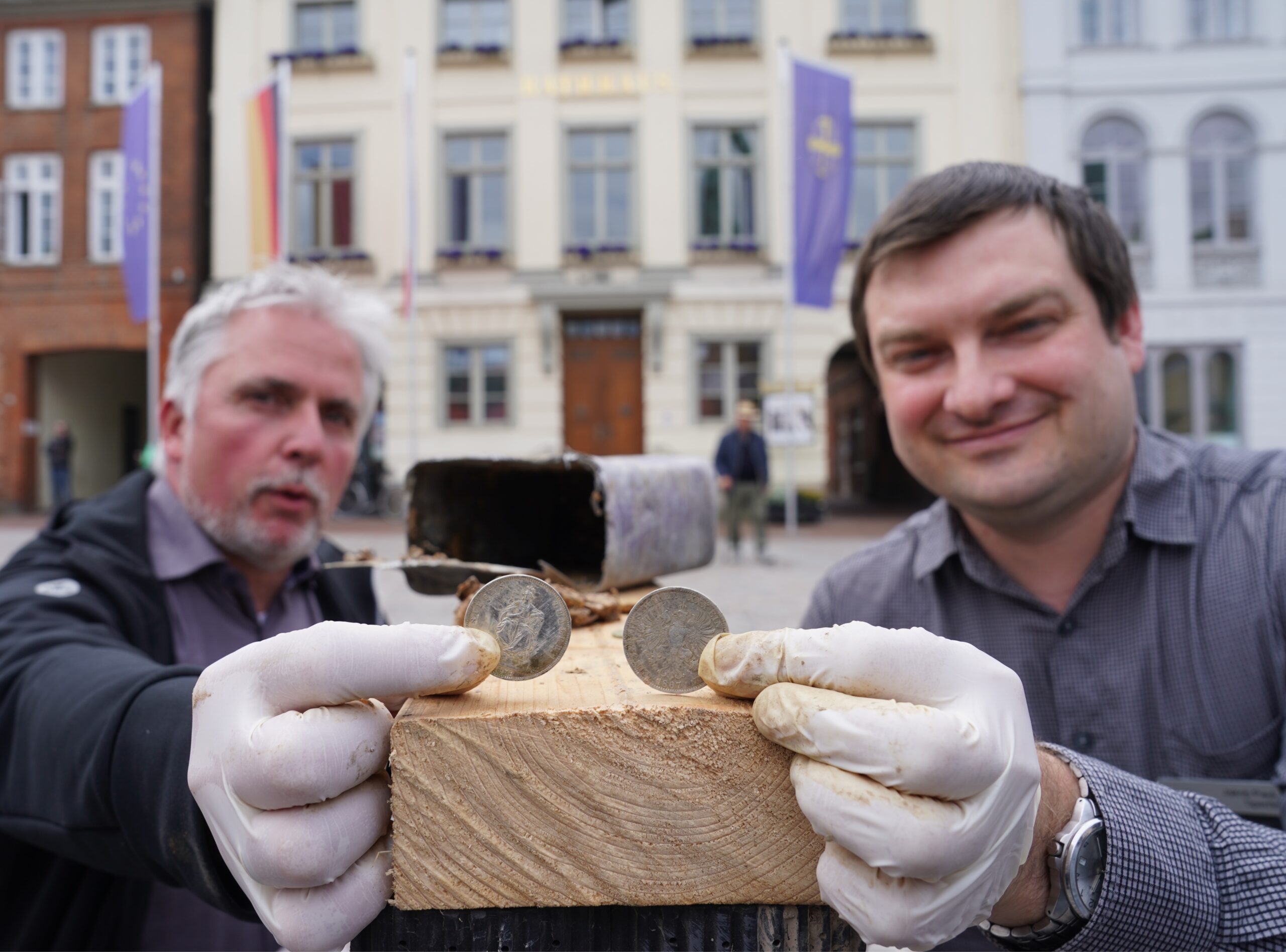 Links der Bürgermeister von Eutin Sven Radestock und rechts Jakob Paul Sperrle, Stadt-Archivar. Beide halten eine Münze in die Kamera