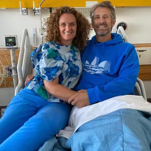 Edwin van der Sar lächelt mit seiner Frau an seiner Seite aus dem Krankenhausbett.