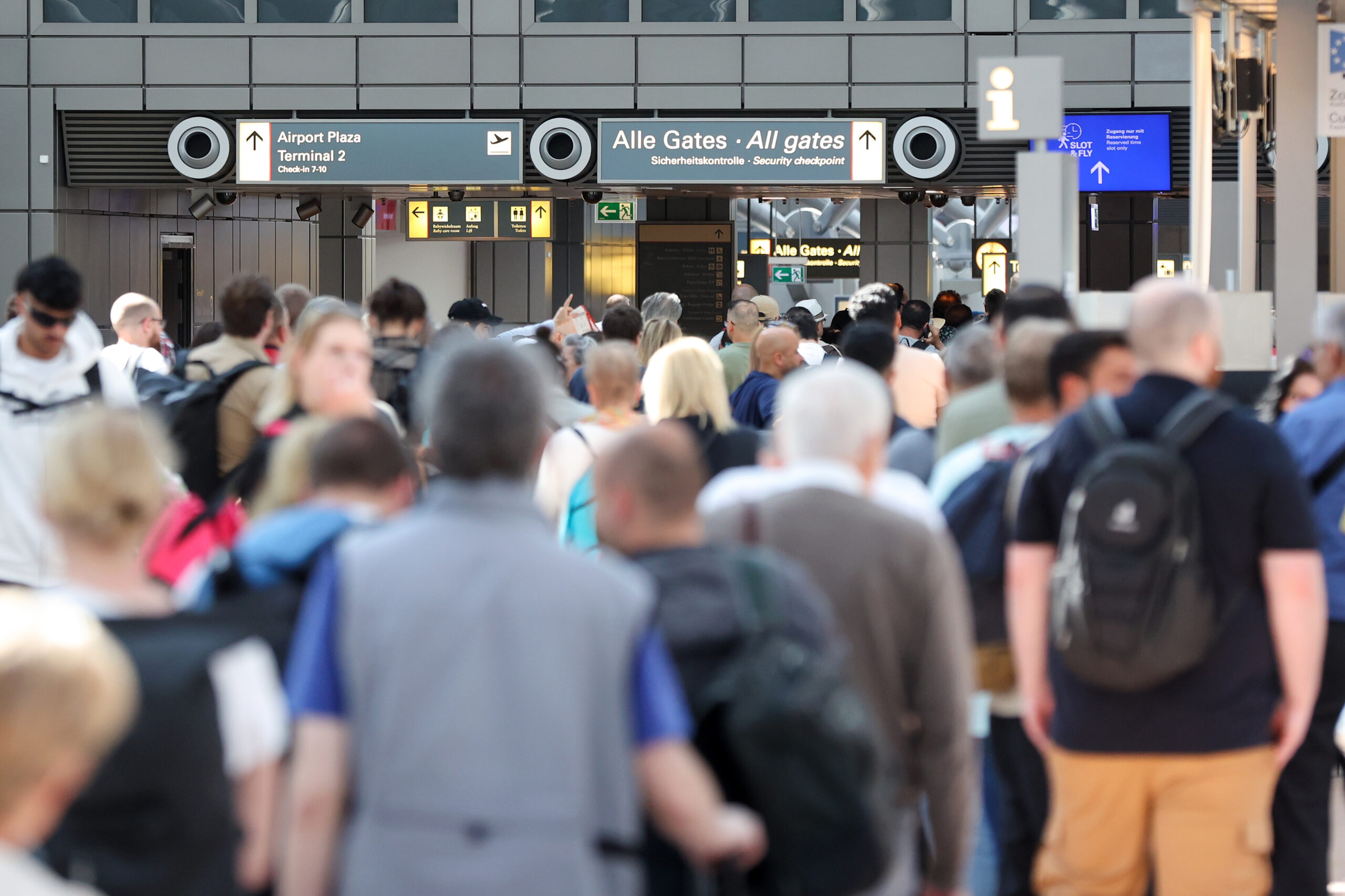 Reisende stehen in einer langen Schlange vor der Sicherheitskontrolle am Hamburger Flughafen an.