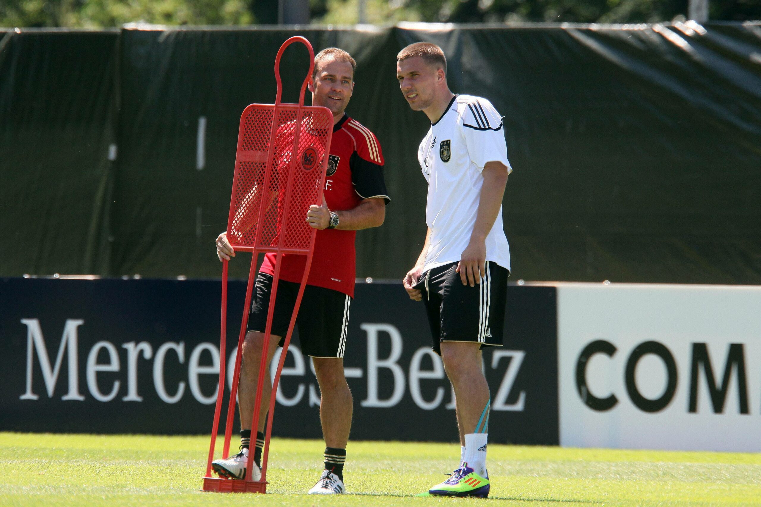 Lukas Podolski und Hansi Flick zusammen auf dem Trainingsplatz im Jahr 2011.