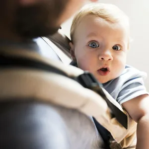 Ein Baby in einer Trage auf der Brust seines Vaters