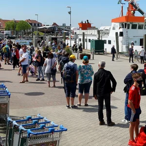 Touristen warten in einer langen Schlange auf die Fähre nach Spiekeroog.