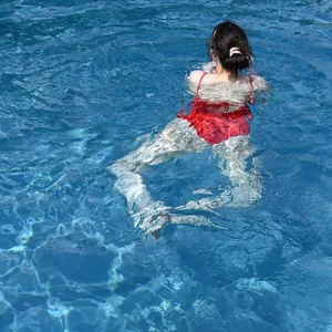 Eine junge Frau in rotem Badeanzug schwimmt im Freibad (Symbolbild).