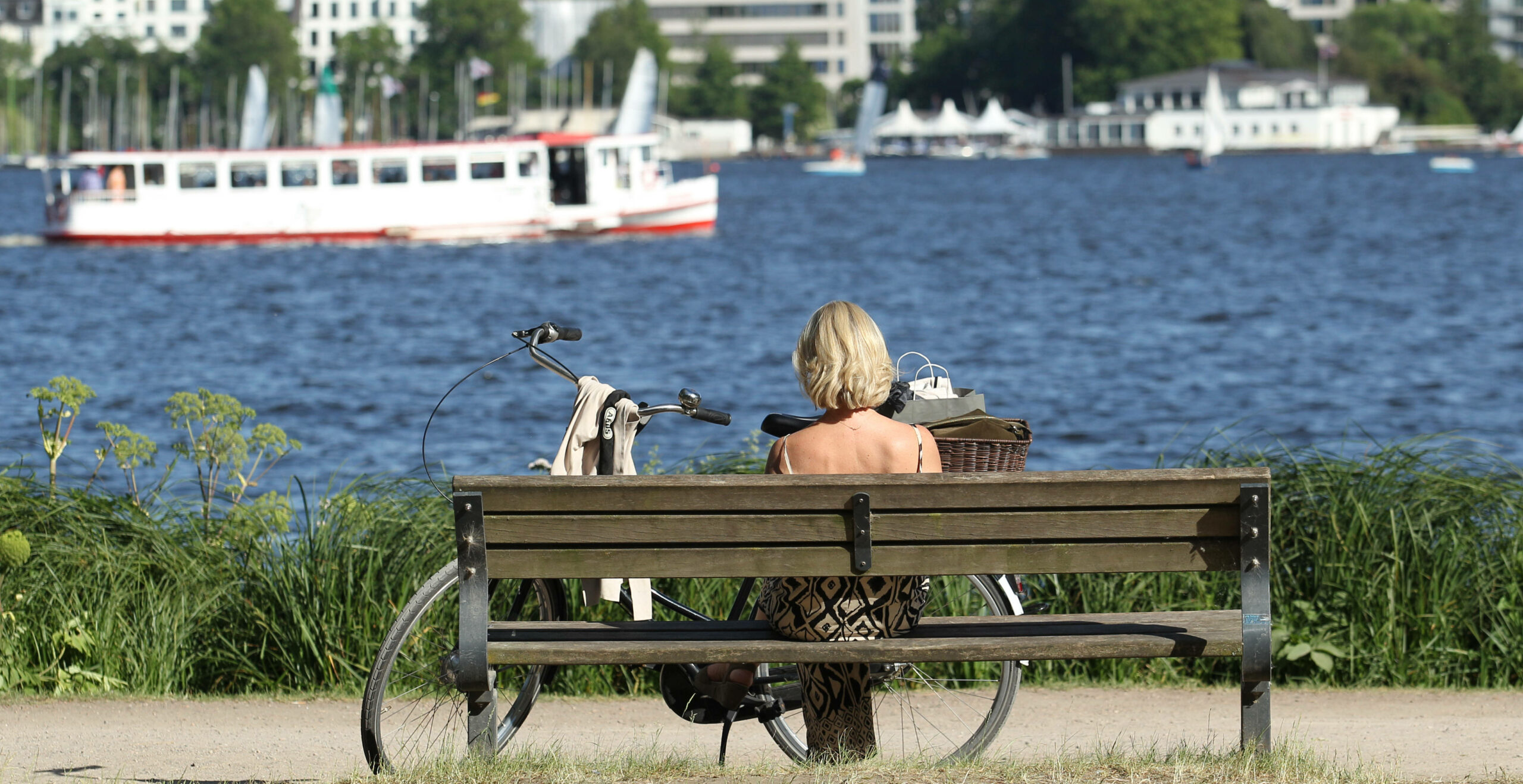 Frau sitzt im Sommer in Hamburg auf Parkbank
