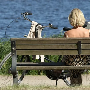 Frau sitzt im Sommer in Hamburg auf Parkbank