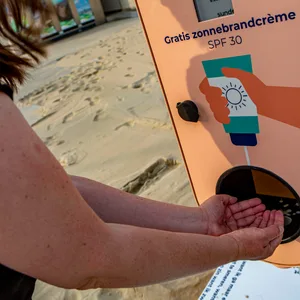 Sonnencreme-Spender am Strand, Frau hält Hände unter den Sensor.