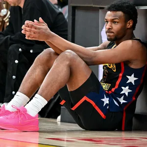Bronny James sitz und lehnt an der Bande am Seitenrand des Basketball-Parketts.