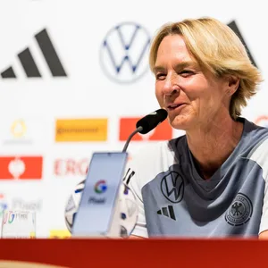 Martina Voss-Tecklenburg lacht auf der Pressekonferenz.
