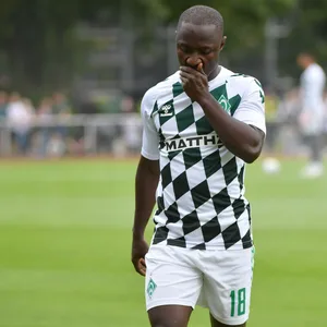 Werder-Profi Keita hält sich die Hand ins Gesicht beim Aufwärmen vor dem Spiel gegen Oldenburg