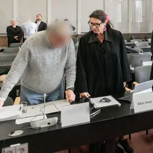 Insgesamt vier Angeklagte stehen mit ihren Verteidigern im Gerichtssaal.