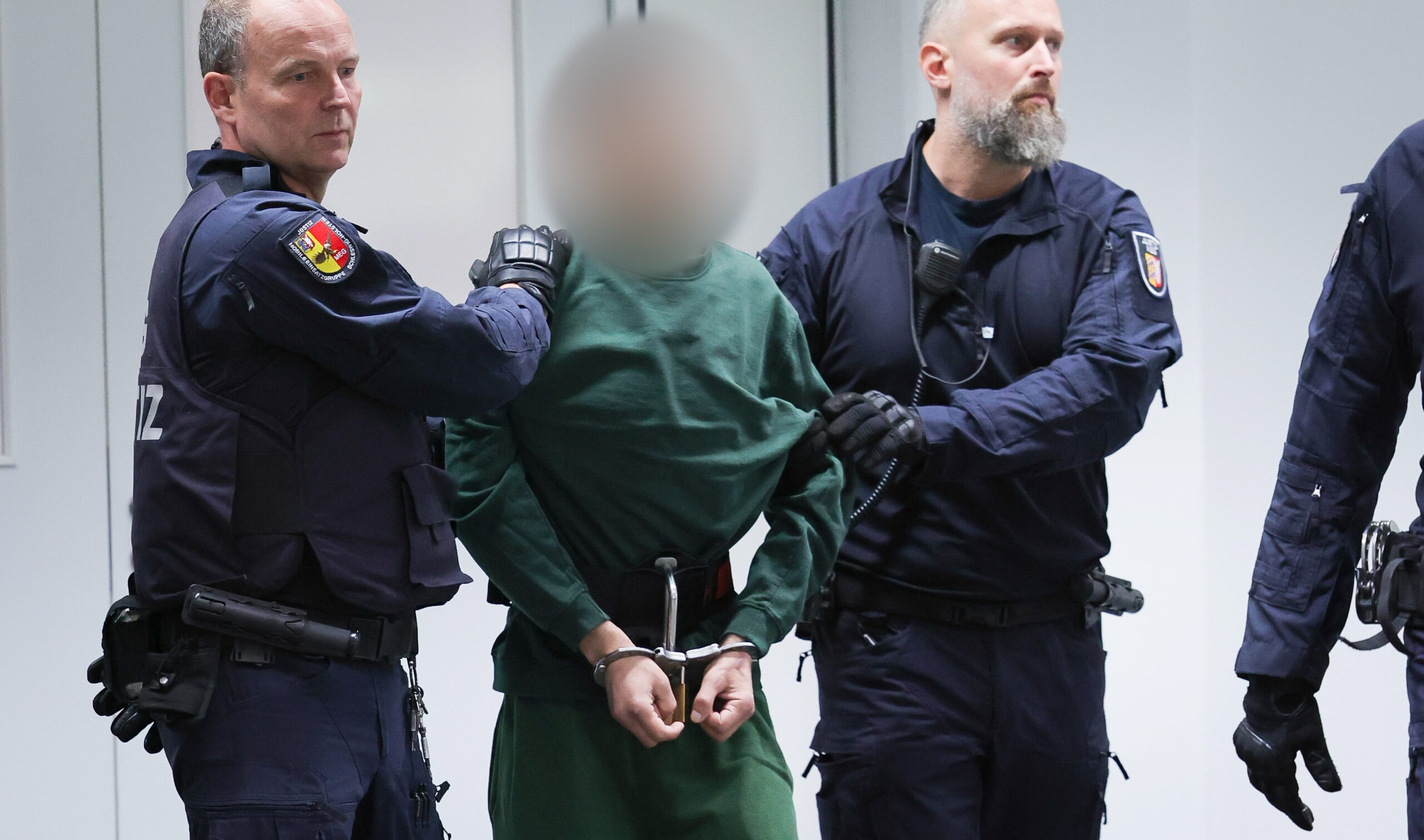 Der Angeklagte Ibrahim A. (dunkelgrüne Hose und Pullover) wird von zwei Polizisten in den Gerichtssaal geführt.