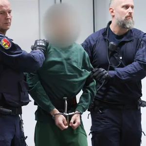 Der Angeklagte Ibrahim A. (dunkelgrüne Hose und Pullover) wird von zwei Polizisten in den Gerichtssaal geführt.
