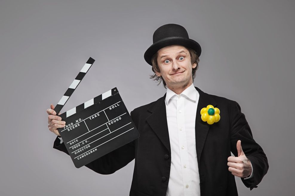 Zauberer mit Hut hält eine Filmklappe in der Hand
