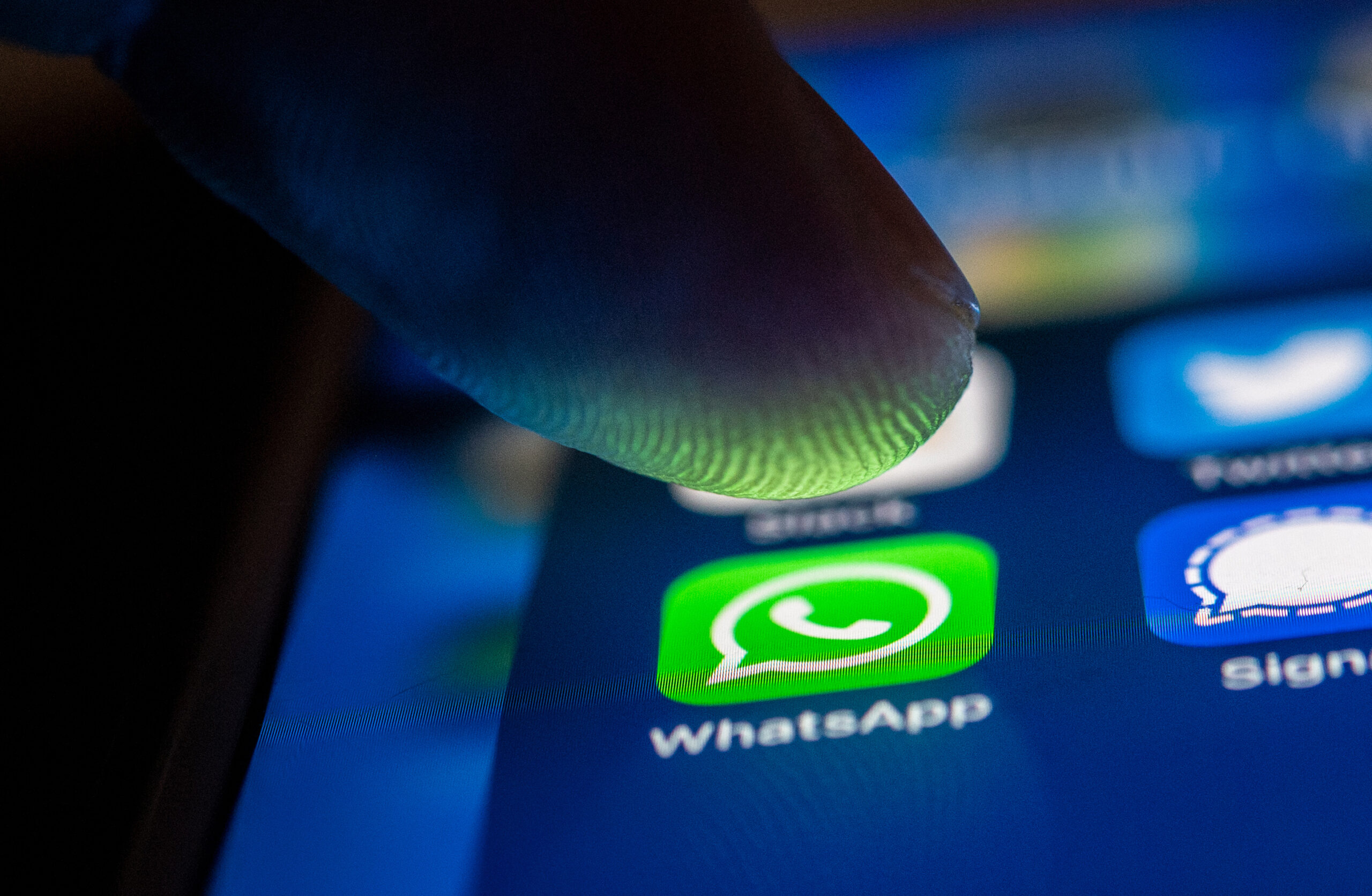Ein Smartphone-Display in Nahaufnahme, ein Finger schwebt knapp über dem WhatsApp-Symbol.