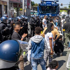 Polizisten haben am Rande des Eritrea-Festivals in Gießen eine Gruppe von Menschen umringt. Im Hintergrund steht ein Wasserwerfer bereit.
