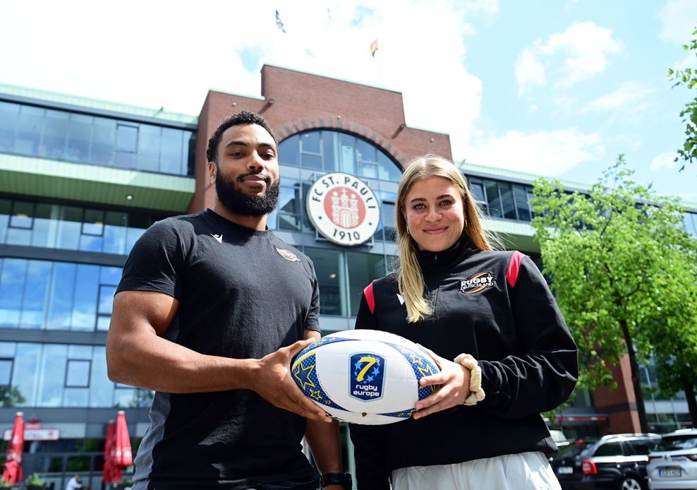 Ben Ellermann und Gesine Adler präsentieren den Rugby vor dem Millerntor-Stadion.