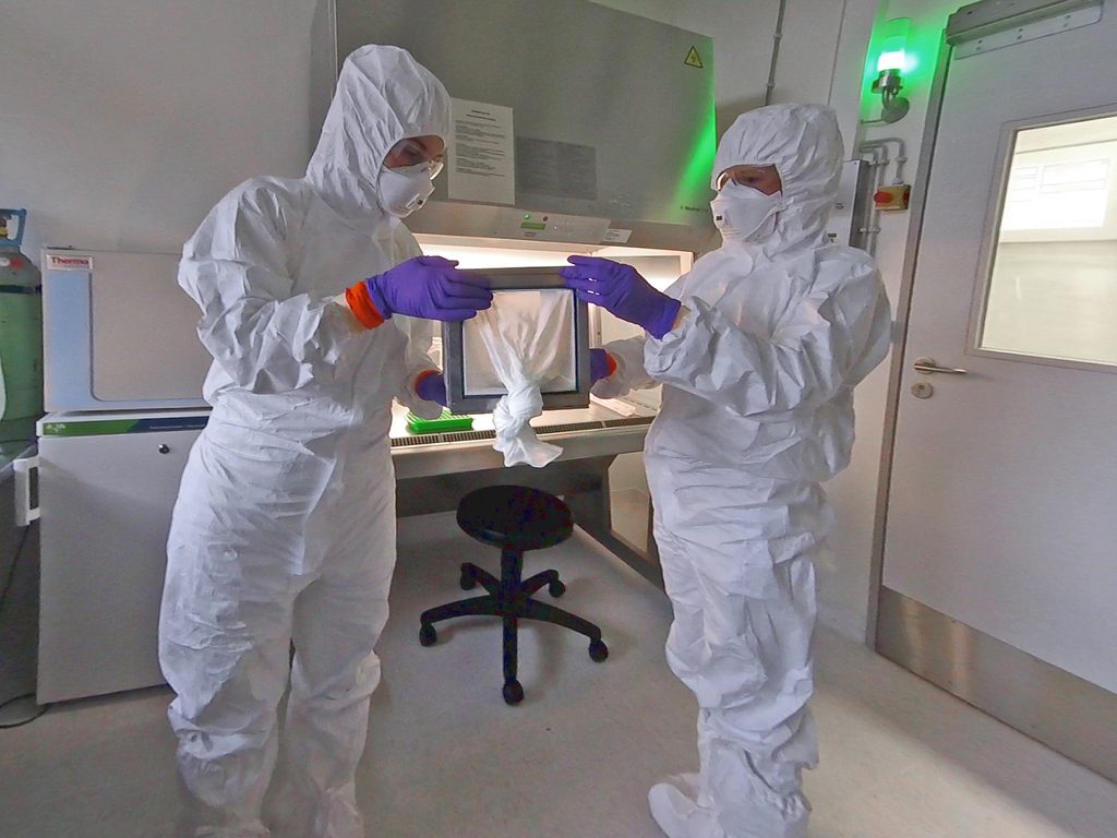 Wissenschaftler bei der Übergabe eines Käfigs voller Mücken