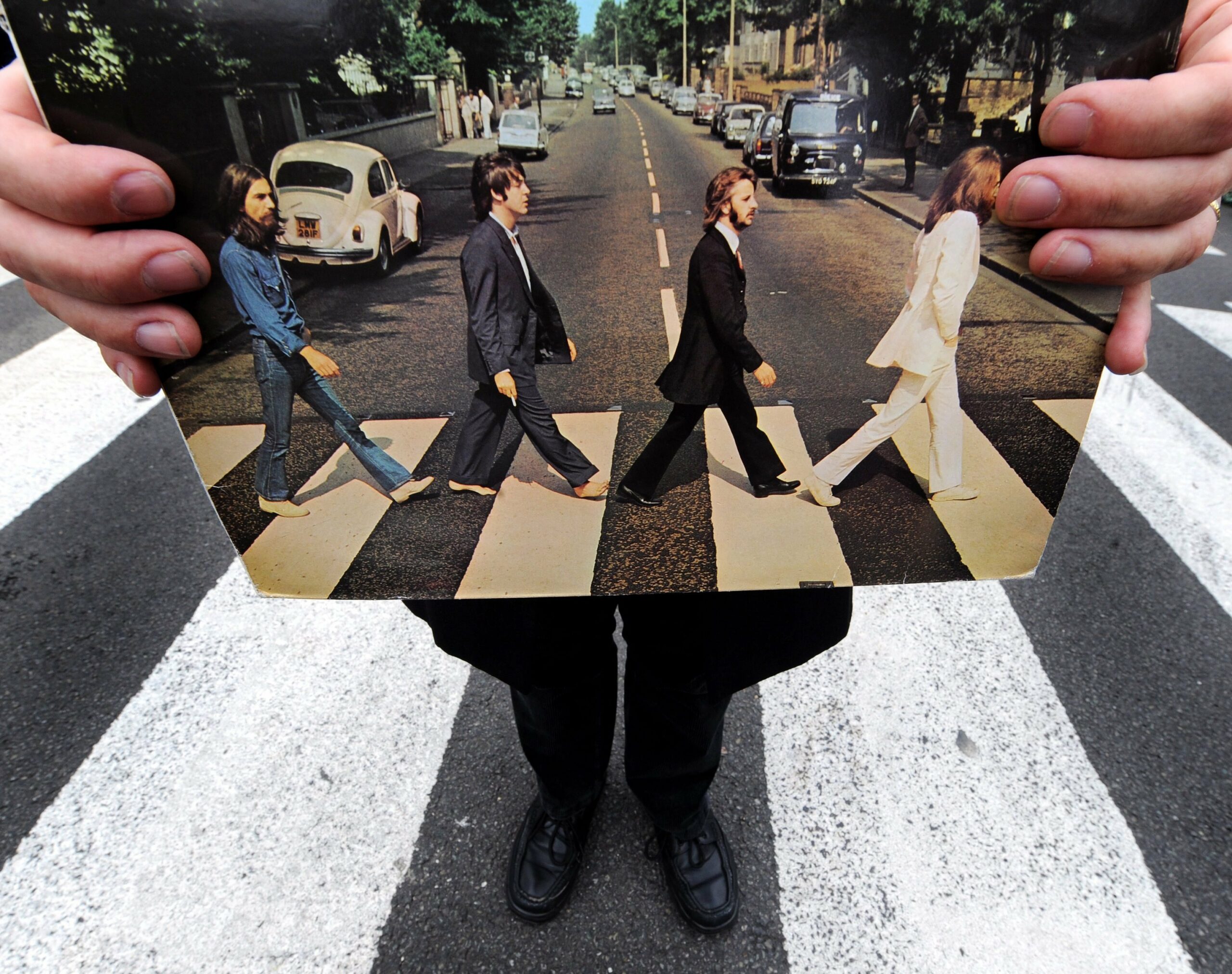 Richard Porter, ein Beatles-Tourguide, hält das Cover des Beatles-Albums „Abbey Road“ auf dem zebrastreifen der gleichnamigen Straße hoch. (Archivbild)