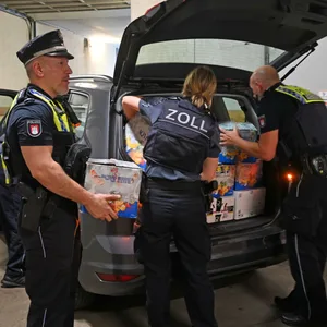 Zollbeamte heben Kartons mit Shisha-Tabak aus einem Auto.