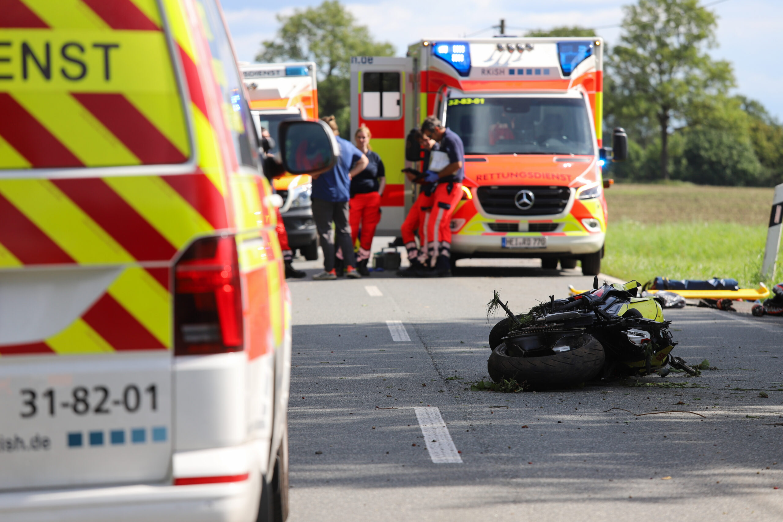 Ein Motorrad liegt auf der Straße, davor und dahinter stehen Rettungswagen.