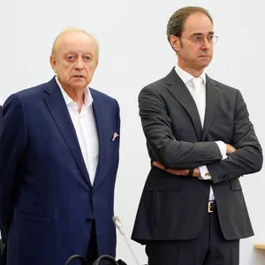 Alfons Schuhbeck, Koch und Unternehmer (M), steht vor Prozessbeginn als Angeklagter zwischen seinen Rechtsanwälten Sascha König (l) und Markus Gotzens im Gerichtssaal im Landgericht München I. (Archivbild)