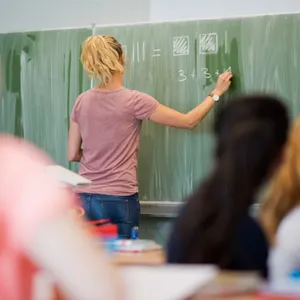 Eine Lehrerin steht an der Tafel.