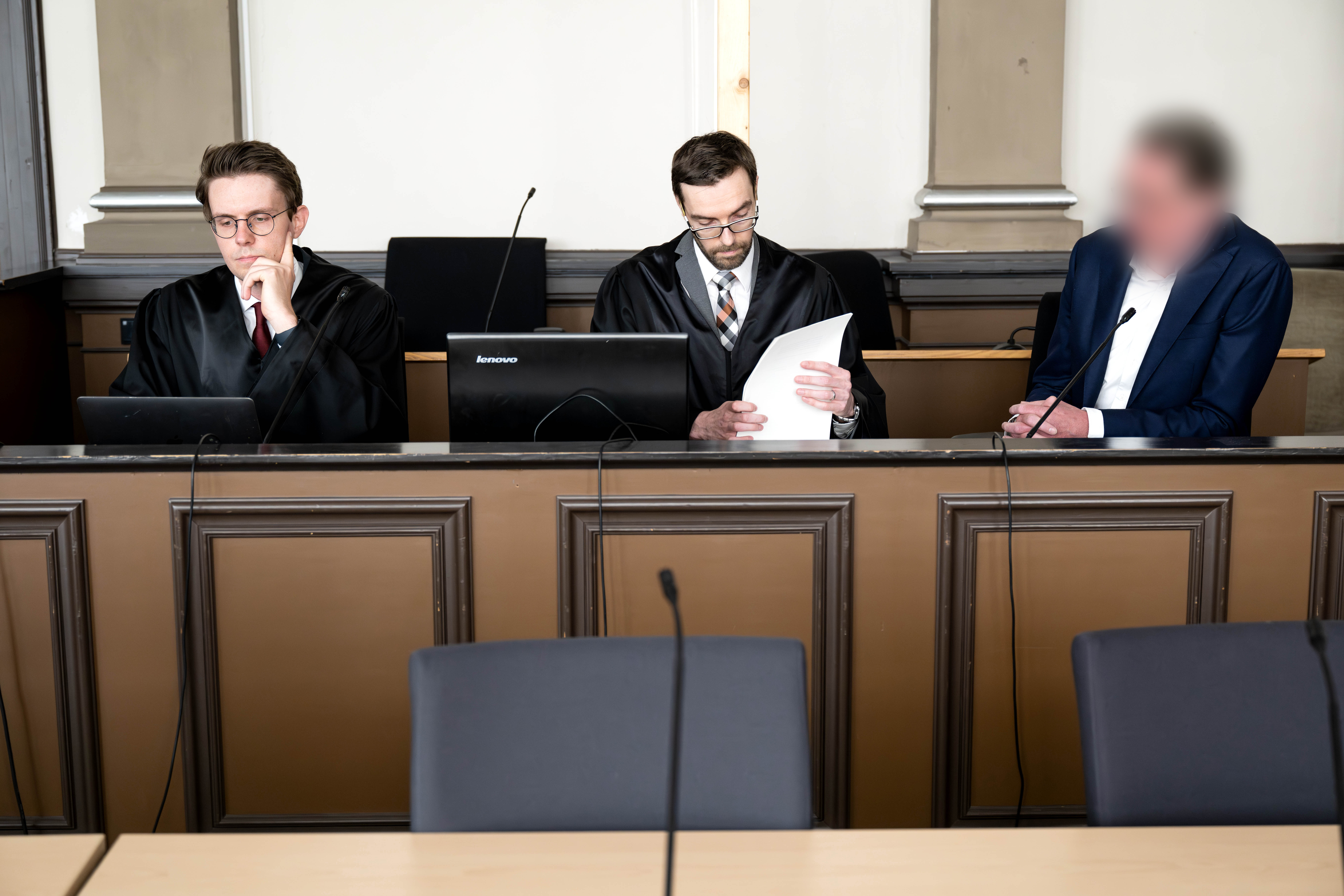 Der Angeklagte (r.) sitzt vor Prozessbeginn mit seinen Anwälten Viktor Volkmann (l) und Sebastian Vogel im Gerichtssaal.