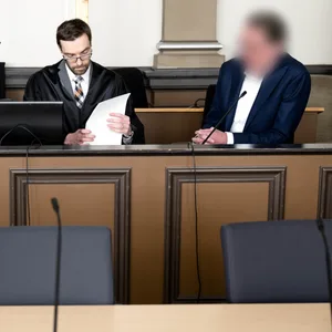 Der Angeklagte (r.) sitzt vor Prozessbeginn mit seinen Anwälten Viktor Volkmann (l) und Sebastian Vogel im Gerichtssaal.
