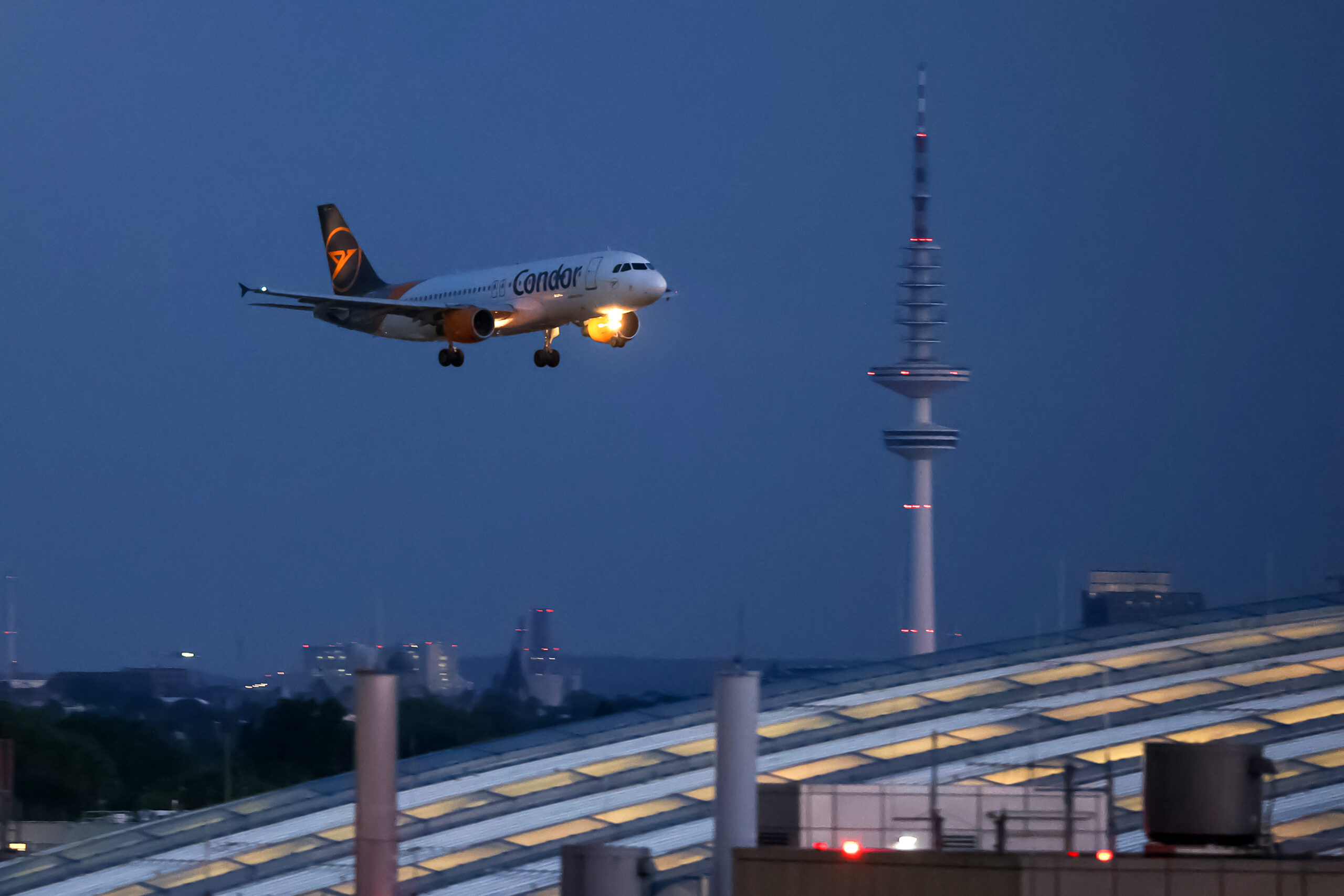 Ein Flugzeug ist abends im Endanflug auf den Hamburger Flughafen.