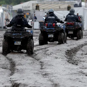 Polizisten auf Quads sind auf dem schlammigen Festivalgelände unterwegs.