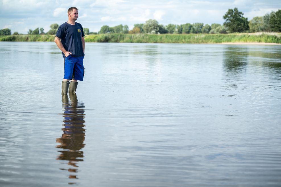 Fischer Andre Schneider steht in der Oder. Die Familie Schneider betreibt einen Fischereihof mit Campingplatz und Imbiss an der Oder.