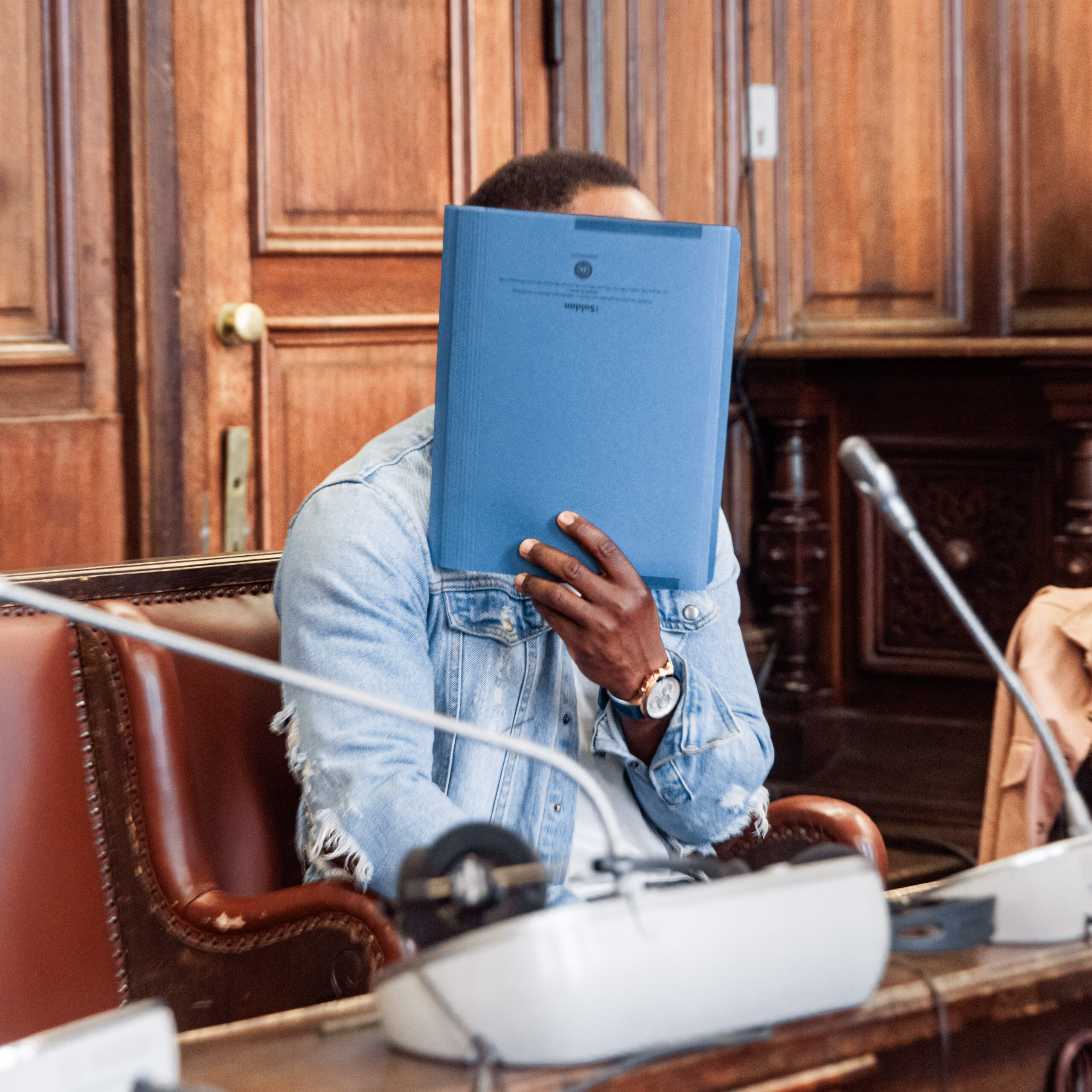 Ibrahim T. im Gerichtssaal, er verbirgt sein Gesicht hinter einem Aktendeckel