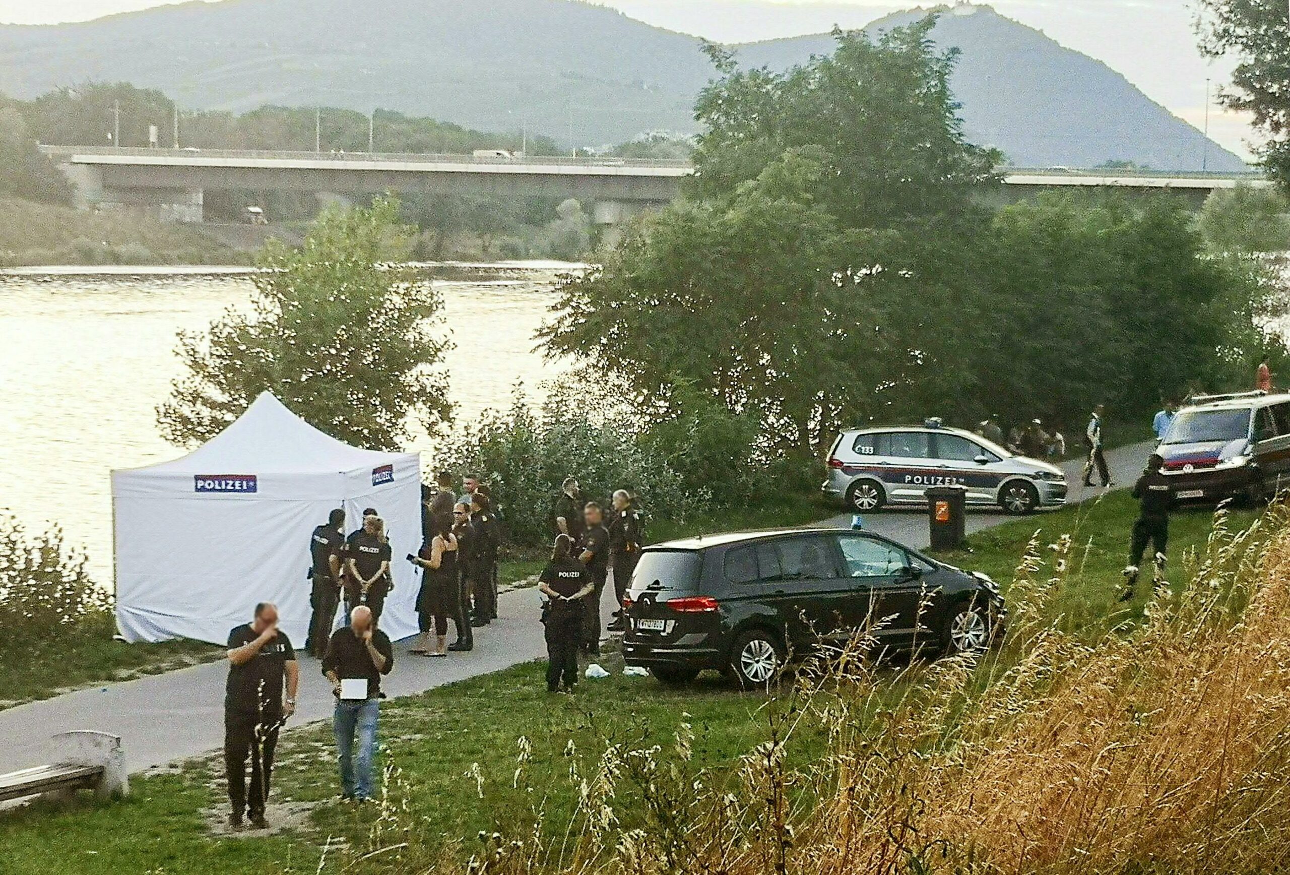 Polizisten ermitteln in am Flussufer. Ein vermisster fünfjähriger Junge ist nach einer Hammerattacke auf seine Mutter tot in einem Seitenarm der Donau gefunden worden.