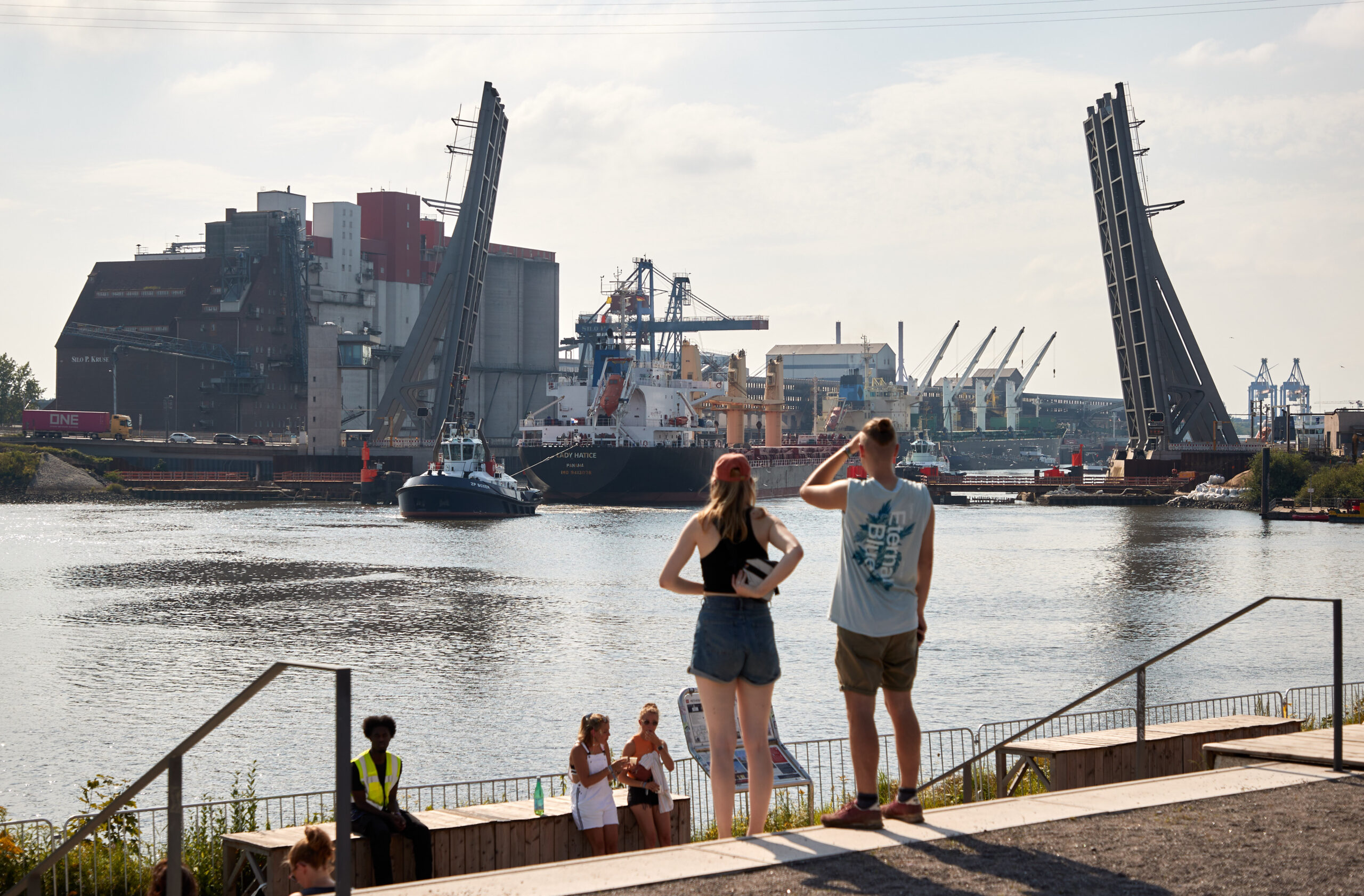 Festivalbesucher stehen bei sommerlichem Wetter auf dem Dockville-Gelände im Hafengebiet von Wilhelmsburg.