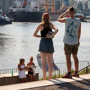 Festivalbesucher stehen bei sommerlichem Wetter auf dem Dockville-Gelände im Hafengebiet von Wilhelmsburg.