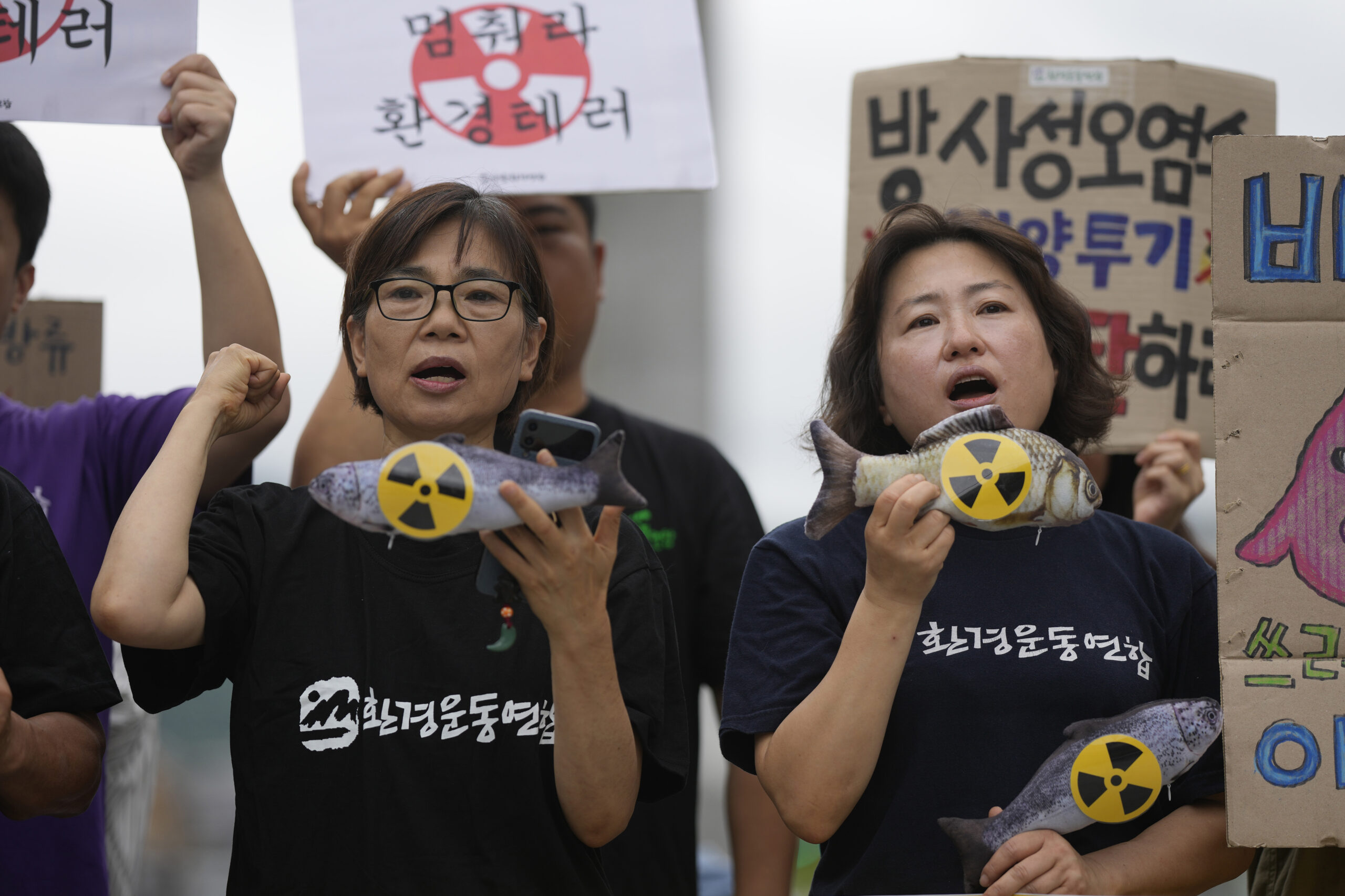 Man siegt zwei Frauen, die Protestieren und Schilder mit durchgestrichenen Atomkraft-Symbolen.