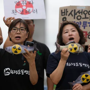 Man siegt zwei Frauen, die Protestieren und Schilder mit durchgestrichenen Atomkraft-Symbolen.
