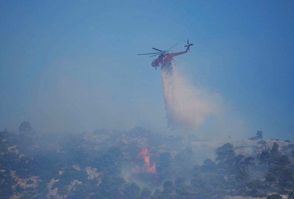 Ein Hubschrauber wirft Wasser über einem Waldbrand auf dem Berg Parnitha ab.