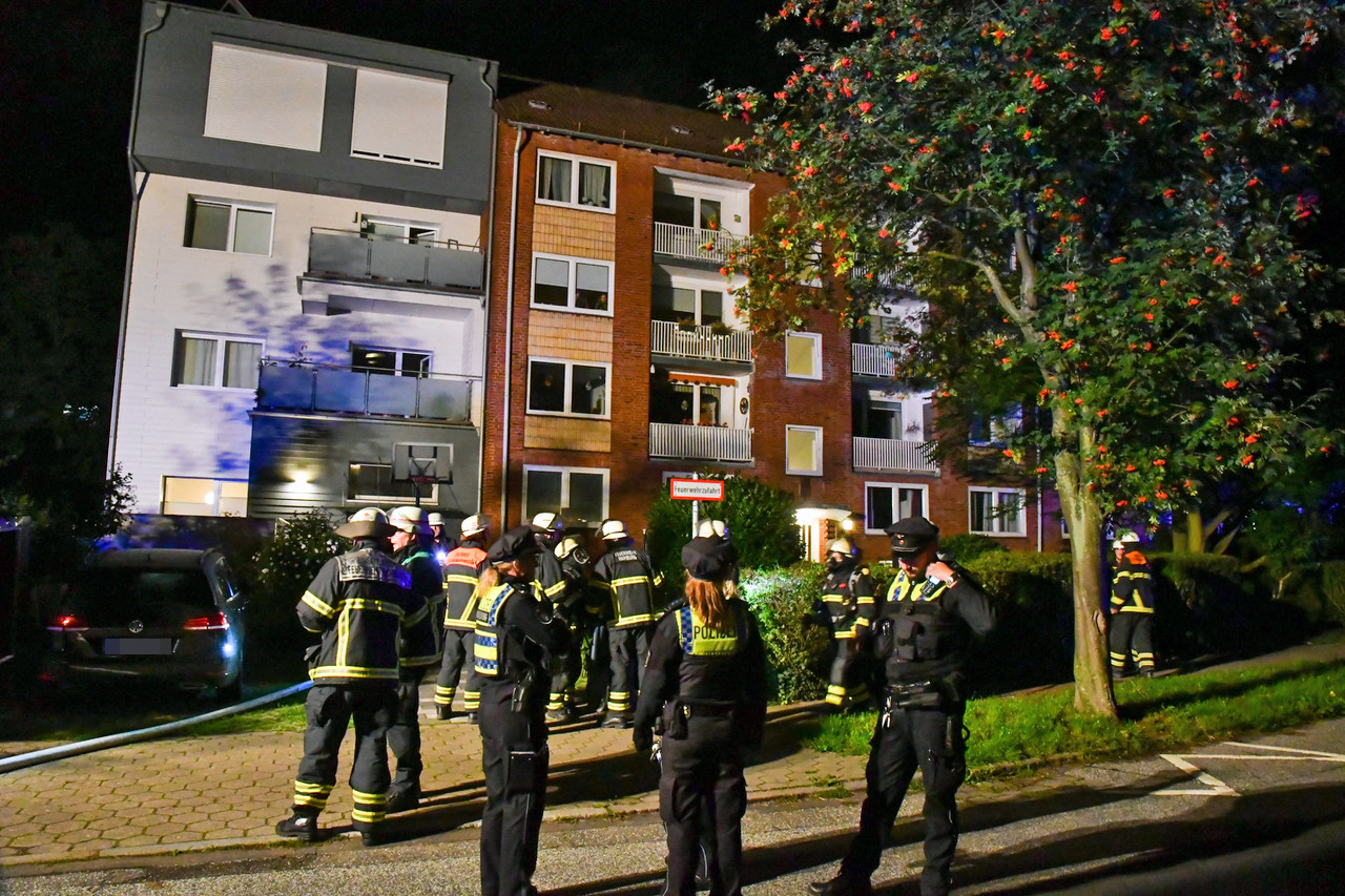 Einsatzkräfte von Polizei und Feuerwehr stehen vor dem Haus in Borgfelde.