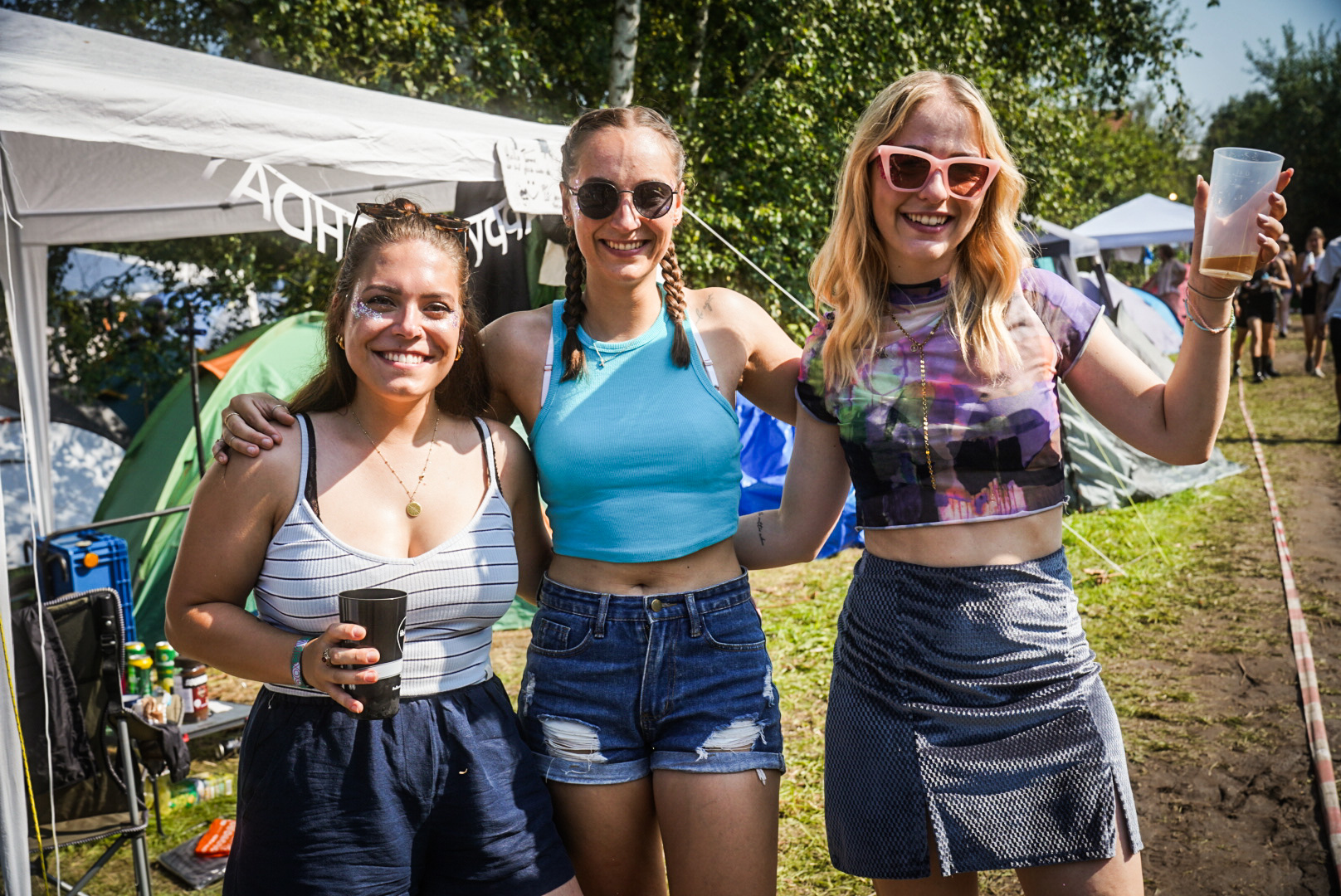 Drei lächelnde Frauen auf dem Campingplatz des Festivals